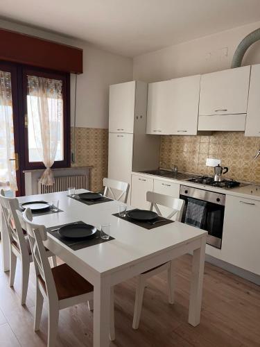 Casa Udine Charme 5 posti letto的厨房配有白色的桌子、椅子和炉灶。