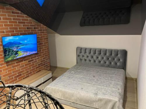 RELAX VILLA的卧室配有1张床和1台砖墙电视