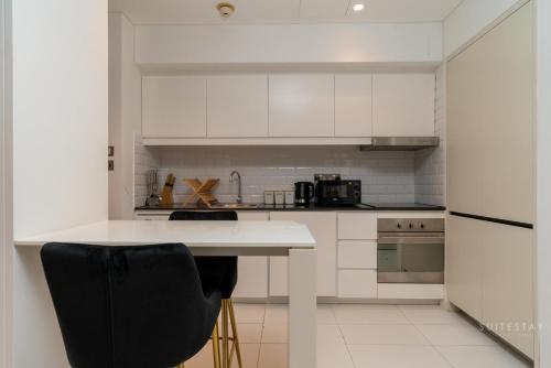 迪拜Skyline Burj Facing Suite的厨房配有白色橱柜和黑椅