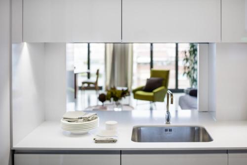 巴塞罗那The Onsider - Luxury 4 Bedroom Apartment的一间带水槽的白色厨房和一个客厅