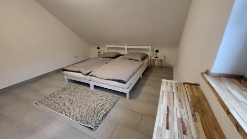 萨尔布吕肯Ferienwohnung am Grumbach的卧室配有白色的床和地毯。