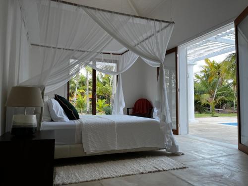 MaxaranguapeMaracajau Luxury Home - Villa-Mar-a-Villa的一间卧室配有一张带天蓬的白色床