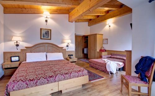 科尔蒂纳丹佩佐Hotel Des Alpes的一间带两张床的卧室,位于木天花板的房间