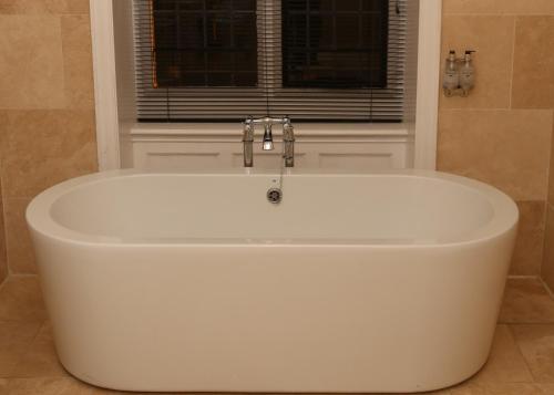 布莱克伍德梅斯庄园乡村酒店的带窗户的浴室内的白色浴缸