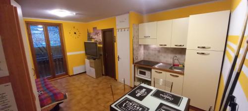 福波洛FOPPOLO apt.C101的一间设有黄色墙壁和白色橱柜的小厨房