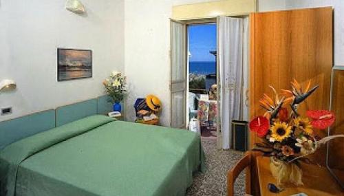 里米尼Hotel Bella Romagna的一间卧室设有一张绿色的床,享有海景
