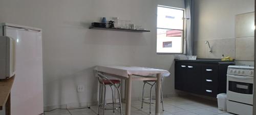 马里利亚kitnet Marilia 2的厨房配有一张桌子和两张凳子