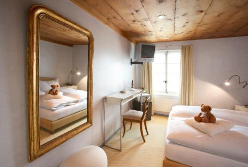 苏西Romantik Hotel de L'Ours的带两张床和镜子的客房