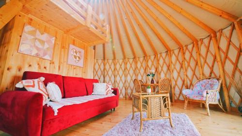 WolanyGlamping Niebiańska Osada Jurty Dolnośląskie & SPA的客厅配有红色的沙发和两把椅子