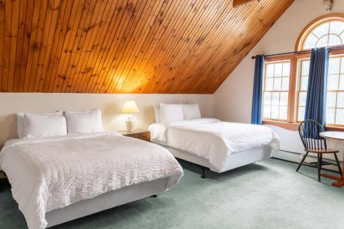 萨拉纳克莱克Sara Placid Inn & Suites的配有木天花板的客房内的两张床