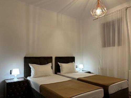 AfumaţiPensiunea Le Patrick的一间卧室配有两张床和吊灯。