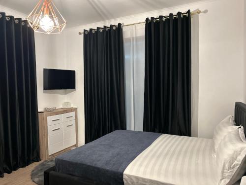 AfumaţiPensiunea Le Patrick的一间卧室配有黑色窗帘、一张床和电视。