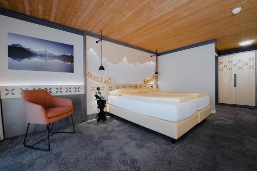格林德尔瓦尔德Hotel Central Wolter - Grindelwald的一间卧室配有一张大床和一把椅子