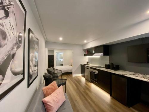 悉尼Luxury inner-west flat w/ breakfast and coffee included!的一间带厨房的房间和一间带沙发的客厅