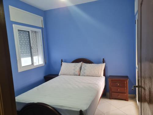 丹吉尔appart hotel tanger gzenaya的蓝色的卧室设有床和窗户