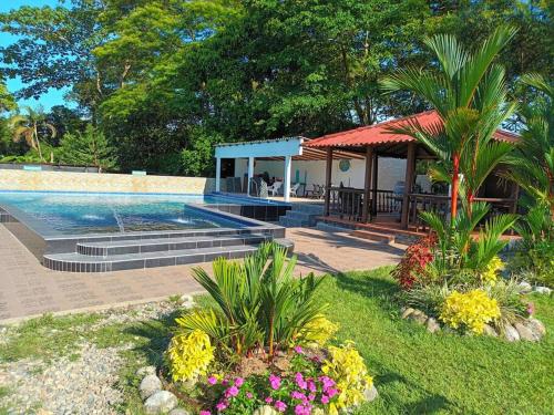 比亚维森西奥HOSPEDAJE FAMILAR CAMPESTRE "Villa Alondra"的一个带凉亭和一些鲜花的游泳池