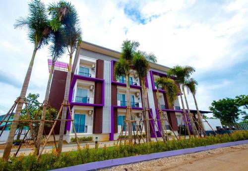 甘烹碧FIG精品酒店的一座紫色的建筑,前面有棕榈树