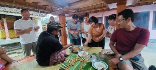 PetangPinge Traditional Village的一群人站在桌子旁吃着食物