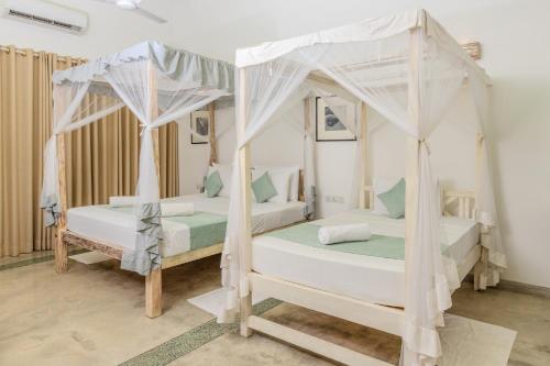 乌纳瓦图纳奥洛拉住宿加早餐旅馆的配有两张天蓬床的客房内的两张床