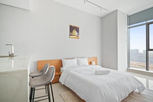 迪拜Newly Built Luxury Apt - Pool的白色卧室配有床和椅子
