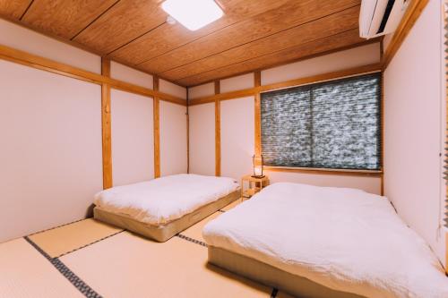 关市Yuzawa Onsen Lodge 1min to LIFT A House的带窗户的客房内的两张床