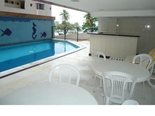 累西腓Flat em Recife的一个带白色桌椅的游泳池、桌子和游泳池
