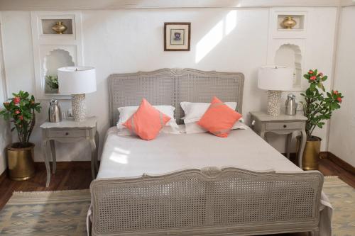 MaheshwarAhilya Fort的一间卧室配有带橙色和白色枕头的床