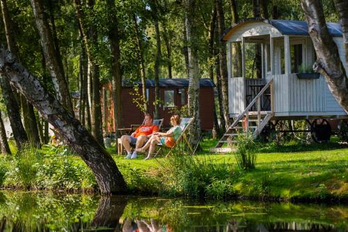 金洛伊Glamping - 25 min Roermond, Maasmechelen & Maastricht的坐在小屋附近长凳上的男女