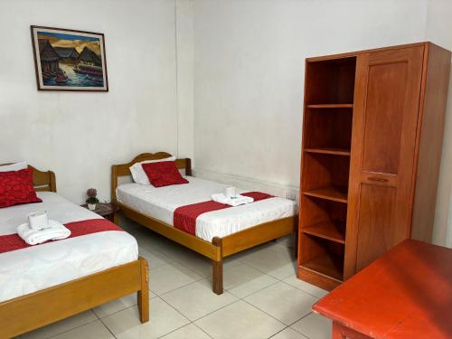 伊基托斯Hospedaje Casa Amazónica Iquitos的一间卧室设有两张床和书架