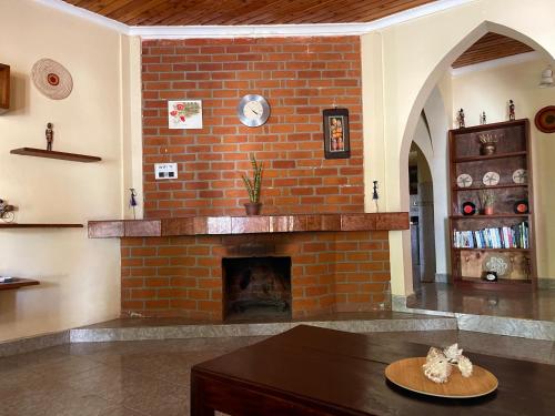 阿鲁沙Toiwo Residence Arusha的客厅设有砖砌壁炉,配有桌子
