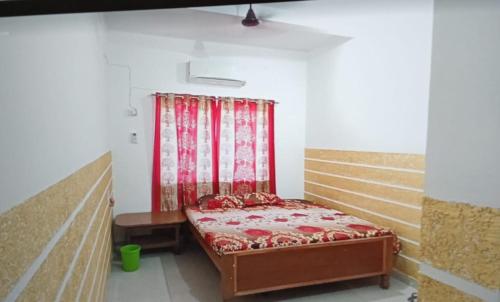 RāmgarhCLASSIC GUEST HOUSE的一张小床,位于一个红色窗帘的房间