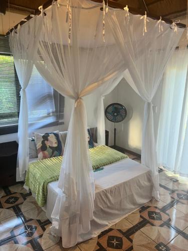 马普托Sunbonani Lodge的卧室配有带白色窗帘的天蓬床
