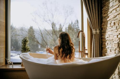 尤格Luxury Chalet Kajmer的坐在浴缸里拿着一杯葡萄酒的女人