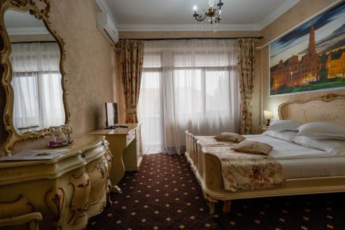 拉姆尼库沃尔恰Hotel Royal的一间卧室配有一张床、镜子和一张书桌