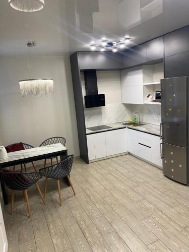 罗夫诺LUX apartment & центр,ЖК Театральний的厨房配有白色橱柜、桌子和冰箱。
