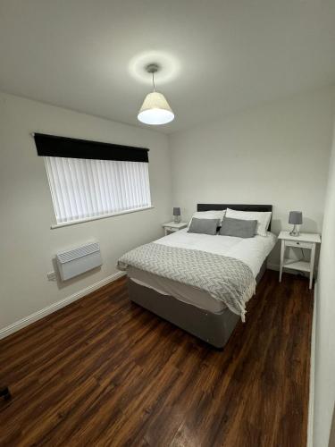 曼彻斯特Manchester Cosy flat close to City Centre and City stadium的卧室配有一张床、木地板和窗户。
