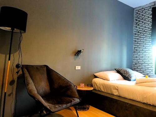 乌隆他尼拉马里拉旅舍的一间卧室配有一张床、一把椅子和一盏灯