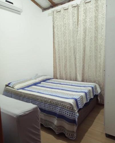 伊利亚贝拉Chalé Ilhabela的一张小床,位于带窗帘的房间