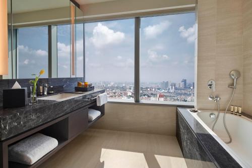 雅加达PARKROYAL Serviced Suites Jakarta的带浴缸的浴室和大窗户