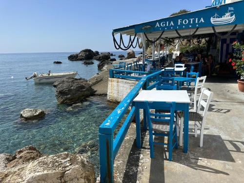 KeramesAgia Fotia Taverna的一间位于水边的带蓝色桌椅的餐厅