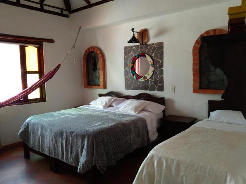 莱瓦镇Hotel El Peregrino De La Villa的一间卧室设有两张床,墙上设有一面镜子