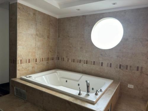 基多Suites & Hotel Gonzalez Suarez的带浴缸的浴室和圆形窗户