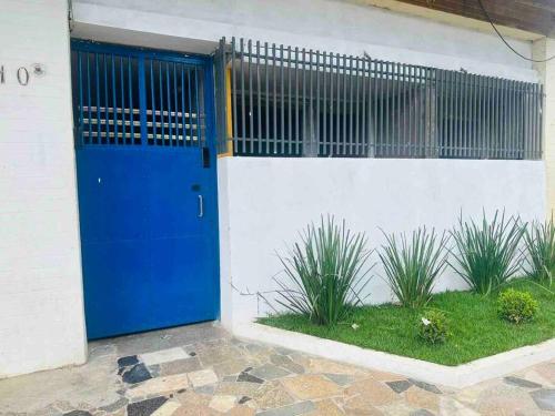 蒙蒂斯克拉鲁斯Apto 16 lindo e confortável的花草丛生的建筑物边的蓝色门