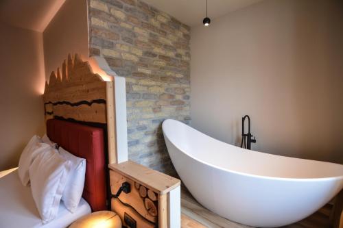 莱德罗西玛多罗酒店的一间带大型白色浴缸和砖墙的浴室