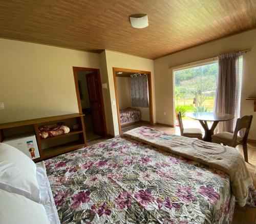 佩德拉阿祖尔Pousada Rural Recanto do Lago的一间卧室配有一张床、一张桌子和一个窗户。