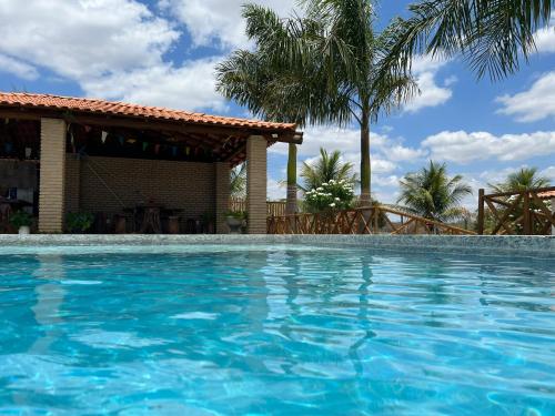SerrinhaSítio recanto das Palmeiras的一座拥有房屋和棕榈树的游泳池