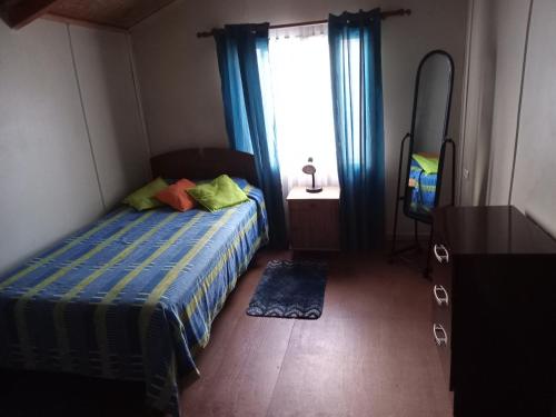 科伊艾科HOSPEDAJE POR TEMPORADA VERANO COYHAIQUE的一间卧室配有一张床、镜子和窗户