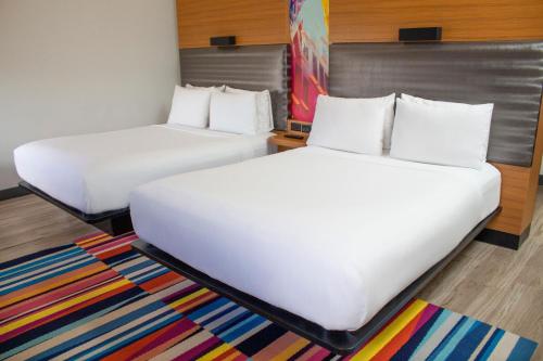 迈阿密雅乐轩迈阿密多拉酒店的宿舍间内的两张床,铺有色彩缤纷的地毯。