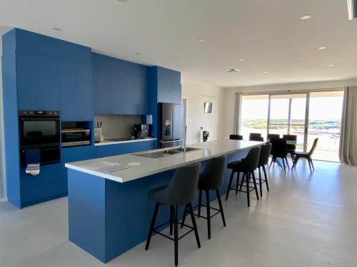 Vivonne Bay库帕兰达梦想度假屋的厨房设有蓝色的墙壁和带酒吧凳的台面。