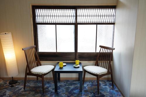 宫津市桜香楽　宮津町家　Sakara Miyazu-Machiya的两把椅子和一张桌子,窗前有两杯马克